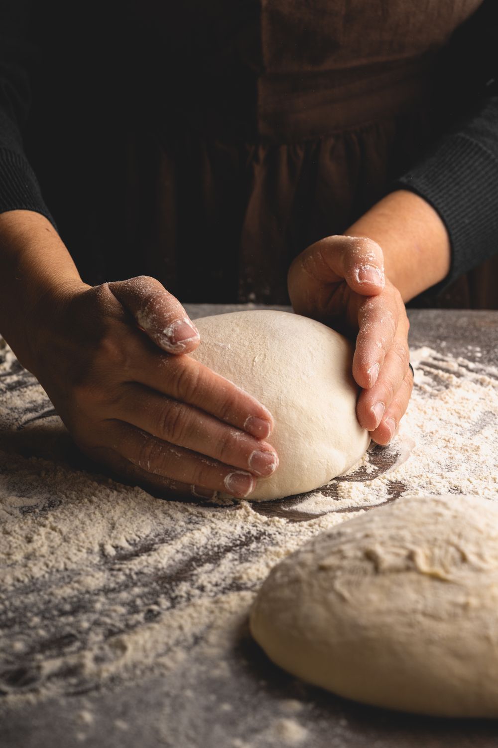 A baker shaping sourdough dough with floured hands